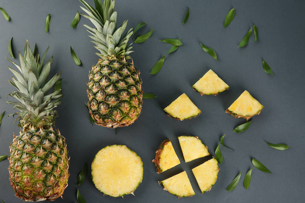 Composizione con ananas freschi interi e tagliati a fette su fondo scuro
 - Foto, immagini