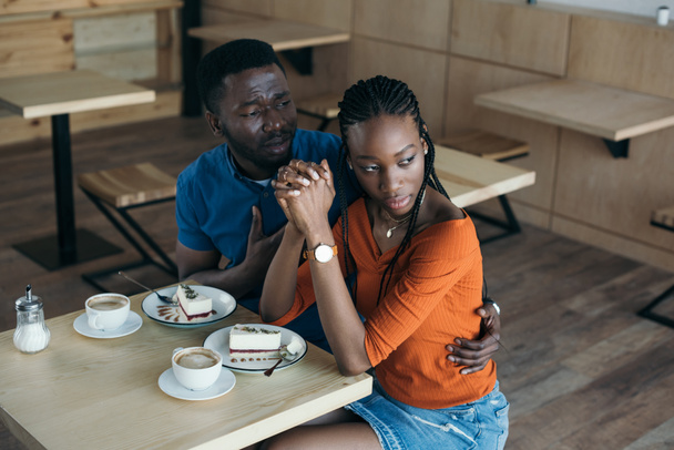 insultado afroamericana mujer con novio sentado a la mesa en la cafetería
 - Foto, imagen