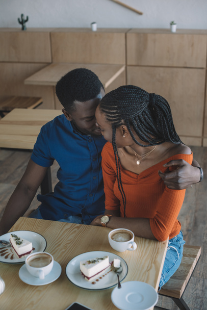 τρυφερό αφρικανική αμερικανική άνθρωπος αγκαλιάζει φίλη για ρομαντική ημερομηνία σε καφενείο - Φωτογραφία, εικόνα