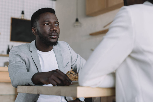 vista parcial del hombre afroamericano pasar tiempo con un amigo en la cafetería
 - Foto, imagen