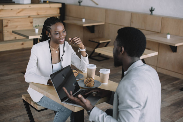 african american friends sitting at table with laptop in coffee shop - Photo, image