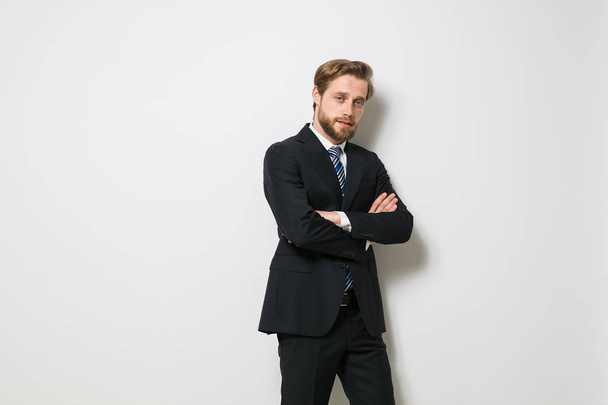 homme élégant confiant debout avec les bras croisés contre un mur blanc en costume et cravate, regardant confiant à côté
 - Photo, image