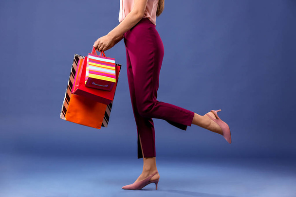 Beautiful young woman with shopping bags on color background - Foto, Imagen