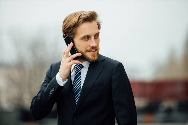 businessman in elegant suit having a nice talk on mobile phone, somewhere in the street between business meetings - Φωτογραφία, εικόνα