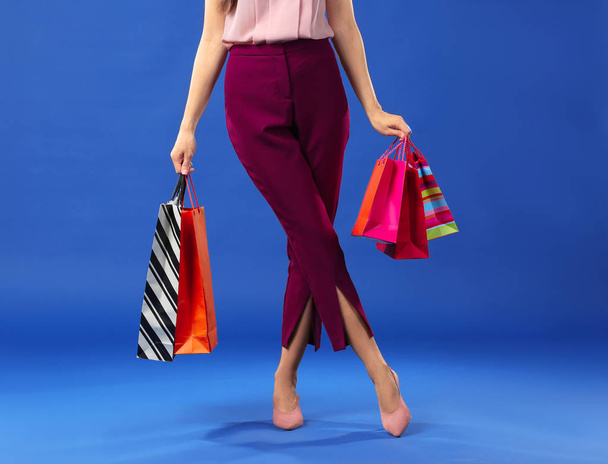 Beautiful young woman with shopping bags on color background - 写真・画像