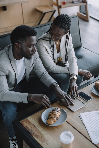 korkea kulma näkymä afrikkalainen amerikkalainen liikemiehet keskustella työstä aikana liiketapaaminen kahvilassa
 - Valokuva, kuva