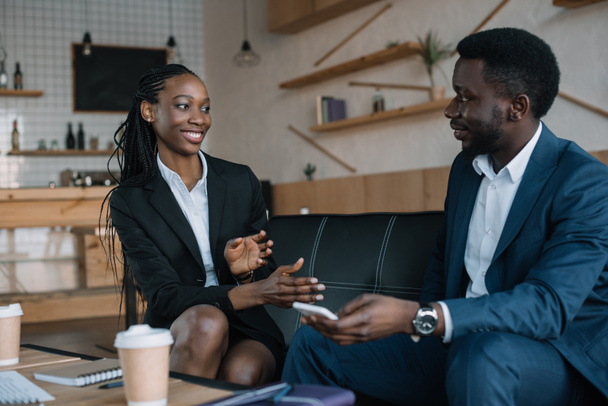 портрет улыбающихся африканских американских деловых партнеров, беседующих в кафе
 - Фото, изображение