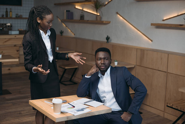 stressed african american businessman with colleague on meeting in cafe - Fotó, kép