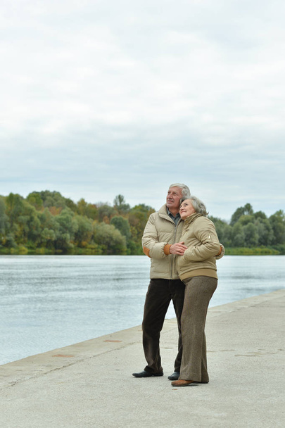 Happy senior couple near water at autumn park  - Foto, afbeelding