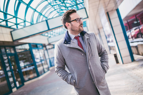 Handsome young businessman walking in front of office building - Photo, image