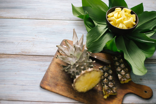 Sliced fresh pineapple in a bowl on the leaves - Fotó, kép