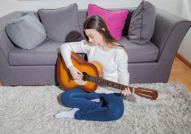 glückliche junge Frau mit Akustikgitarre zu Hause - Foto, Bild