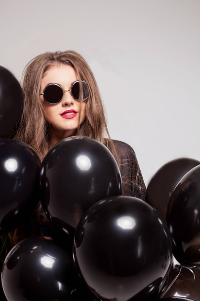Beautiful young girl wearing glasses and hiding behind baloons. - Foto, Imagem