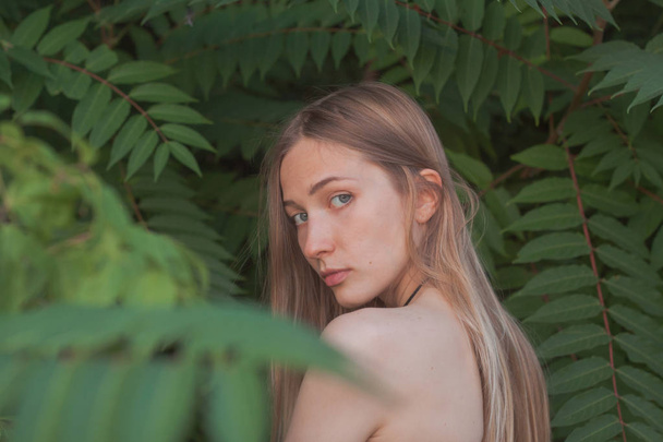 Portrait of beautiful young woman in green leaves, blonde pretty lad - Фото, зображення