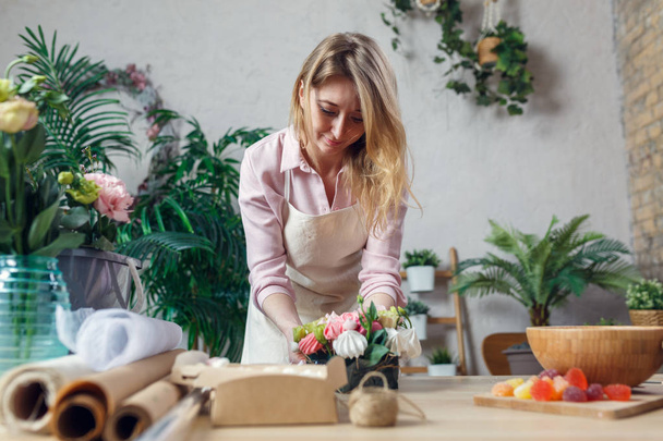 Portrait of florist composing bouquet at table on background of flowers - Foto, immagini