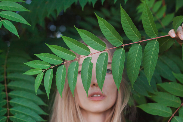 Portrait of beautiful young woman in green leaves, blonde pretty lad - Фото, изображение