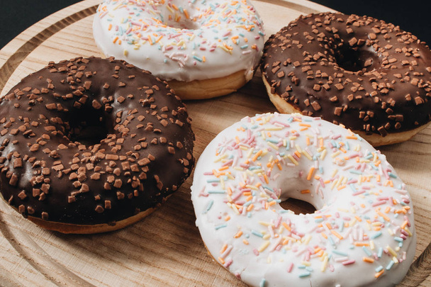 sweet homemade donuts with sugar sprinkles and chocolate glaze on wooden board  - Photo, Image