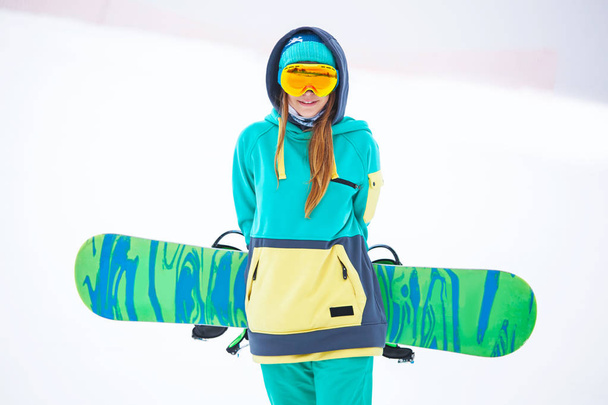 Beautiful young snowboarder girl holding snowboard. - Photo, image