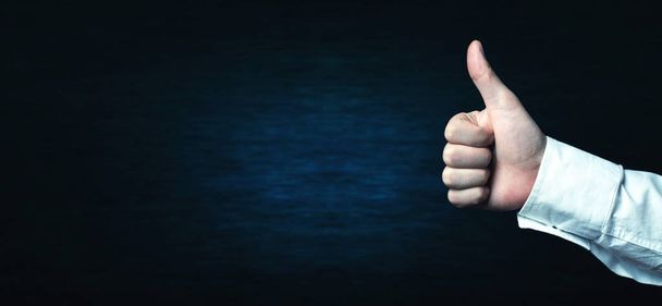 Hand showing thumb up on a blue background. - Foto, afbeelding