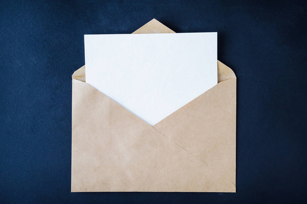 Blank white card in brown enveloop on dark background - Φωτογραφία, εικόνα