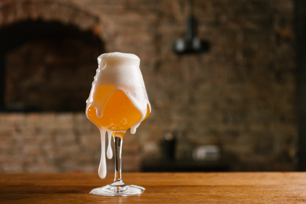 Nahaufnahme von kaltem Bier mit Schaum im Glas auf Holztisch  - Foto, Bild