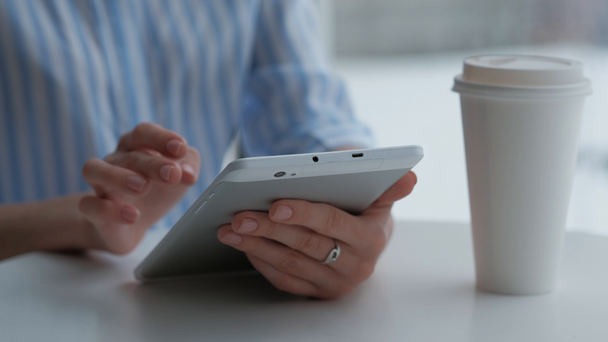 Nainen istuu kahvilassa ja käyttää digitaalista tablettia
 - Materiaali, video