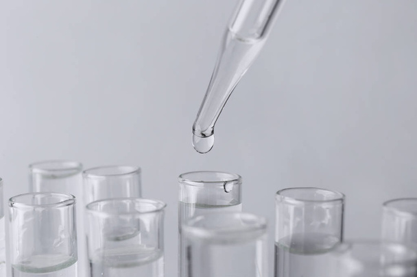 Pipette tropft Probe in Reagenzglas auf hellem Hintergrund, Nahaufnahme - Foto, Bild