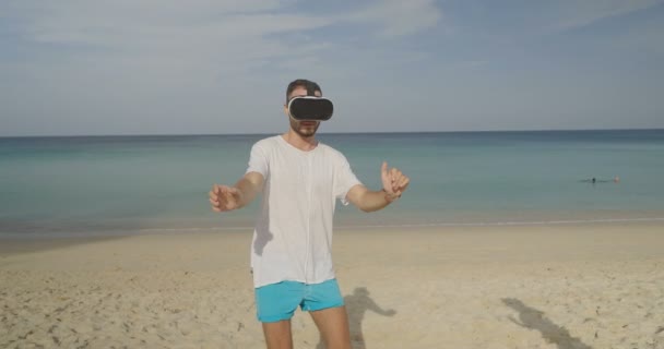 Молодий чоловік використовує окуляри віртуальної реальності, що зустрічаються зі своєю дівчиною на тропічному пляжі над красивим морським і небесним тлом
 - Кадри, відео