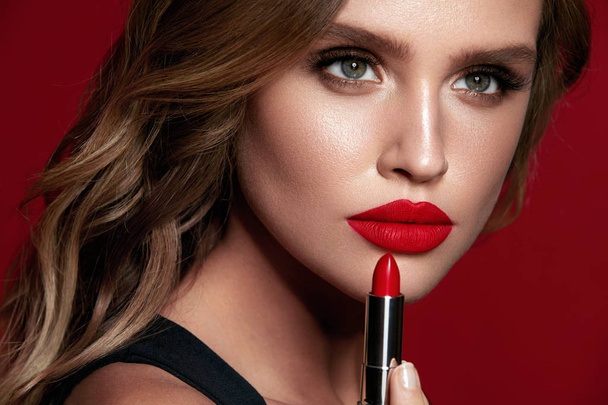 Red Lips. Beautiful Woman With Beauty Makeup Holding Lipstick. - Foto, afbeelding