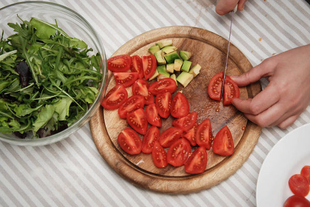 Крій червоний томати на дерев'яні дошки. Процес підготовки здорового салат. Кухня фону. - Фото, зображення