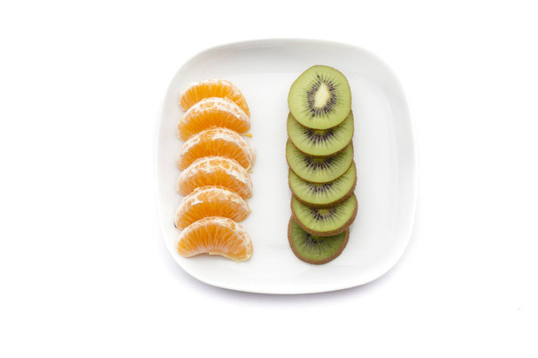 tuoreet hedelmät kiivillä ja mandariineilla valkoisella lautasella. Terveellinen syöminen
 - Valokuva, kuva