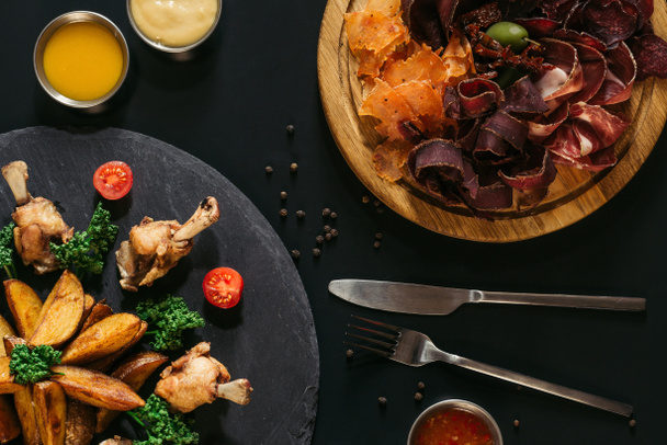vue de dessus des pommes de terre rôties savoureuses avec du poulet et de la viande assortie gastronomique sur noir
 - Photo, image