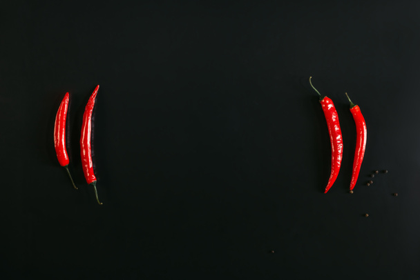 top view of red chili peppers and peppercorns on black background - Foto, immagini