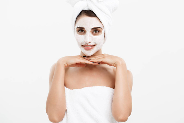 Beauty Skin Care Concept - mooie Kaukasische vrouw gezicht portret toepassen crème masker op haar gezichtshuid witte achtergrond. - Foto, afbeelding