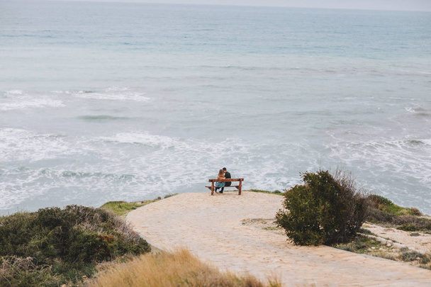 Loving couple walking on the beach, kissing and having fun, wedding ceremony near the rocks and ocean - Фото, зображення
