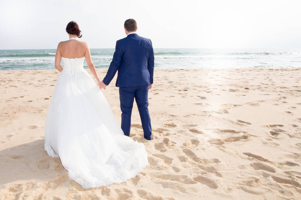 Couples mariés marchent sur la clôture près de la plage Mariée et marié à l'océan
 - Photo, image