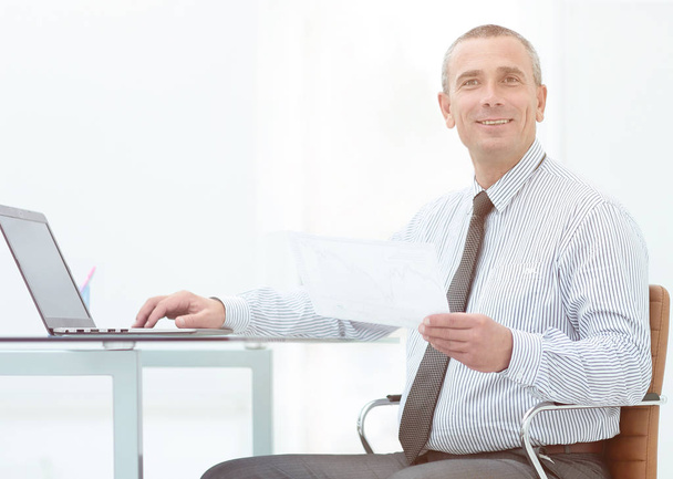 Mature manager sitting at desk in bright office, working - Photo, image
