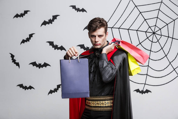 Vampier Halloween Concept - gelukkig knap Kaukasische Vampire bedrijf kleurrijke boodschappentas. - Foto, afbeelding