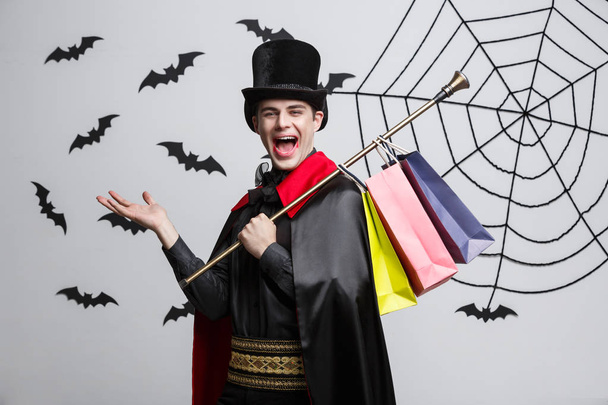 Vampir-Halloween-Konzept - glücklich schöner kaukasischer Vampir mit bunter Einkaufstasche. - Foto, Bild