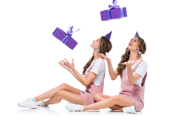 happy beautiful young twins catching falling present boxes on white - Foto, afbeelding
