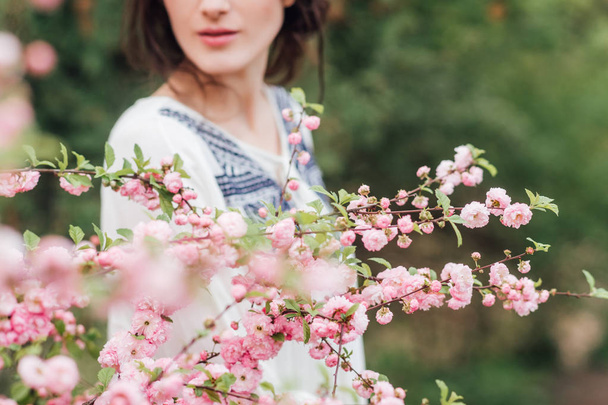 jonge vrouw in de Magnolia's op onscherpe achtergrond - Foto, afbeelding