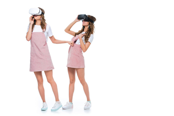 surprised twins watching something in virtual reality headsets isolated on white - Zdjęcie, obraz