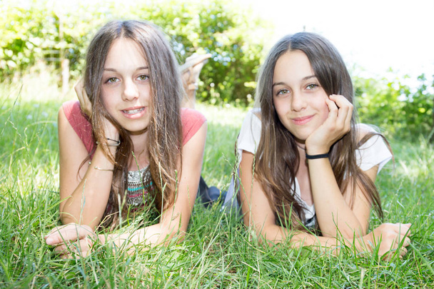 sestry dvojčata leží na zelené louce v létě - Fotografie, Obrázek