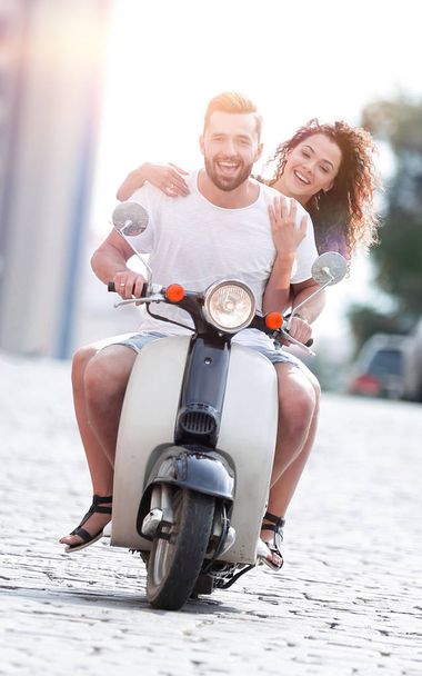 Happy young couple riding a scooter in the city on a sunny day - Foto, Imagen