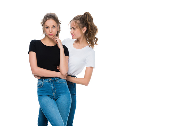 Улыбаясь привлекательный молодой близнец глядя на уверенную сестру изолированы на белом
 - Фото, изображение