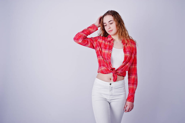 Young girl in red checked shirt and white pants against white ba - Photo, Image