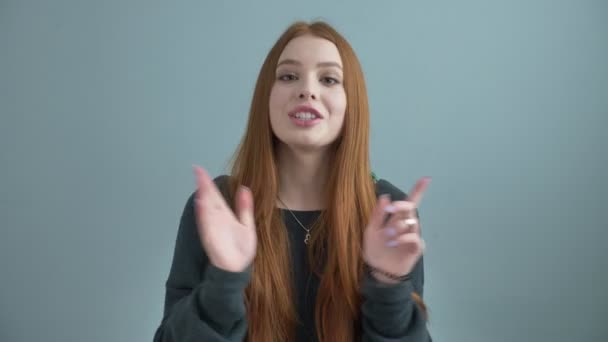 Young beautiful red-haired girl blogger, waving her hand at the camera, hello, telling a story, gesturing, talking, speaking 60 fps - Filmati, video