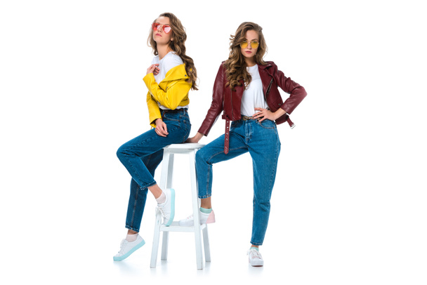 atractivos gemelos con estilo en chaquetas de cuero y gafas de sol con silla de madera aislada en blanco
 - Foto, Imagen