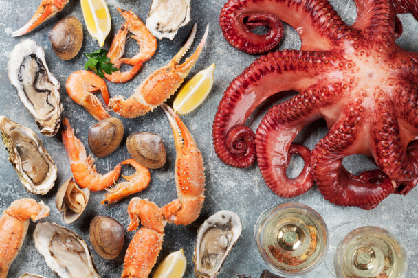 Морепродукты. Осьминог, устрицы, омары, моллюски и белое вино. Вид сверху на каменный стол
 - Фото, изображение