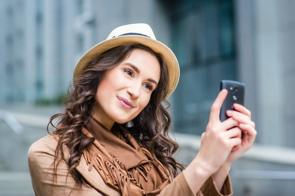 Jeune femme prenant selfie sur smartphone pendant la marche de la ville
 - Photo, image